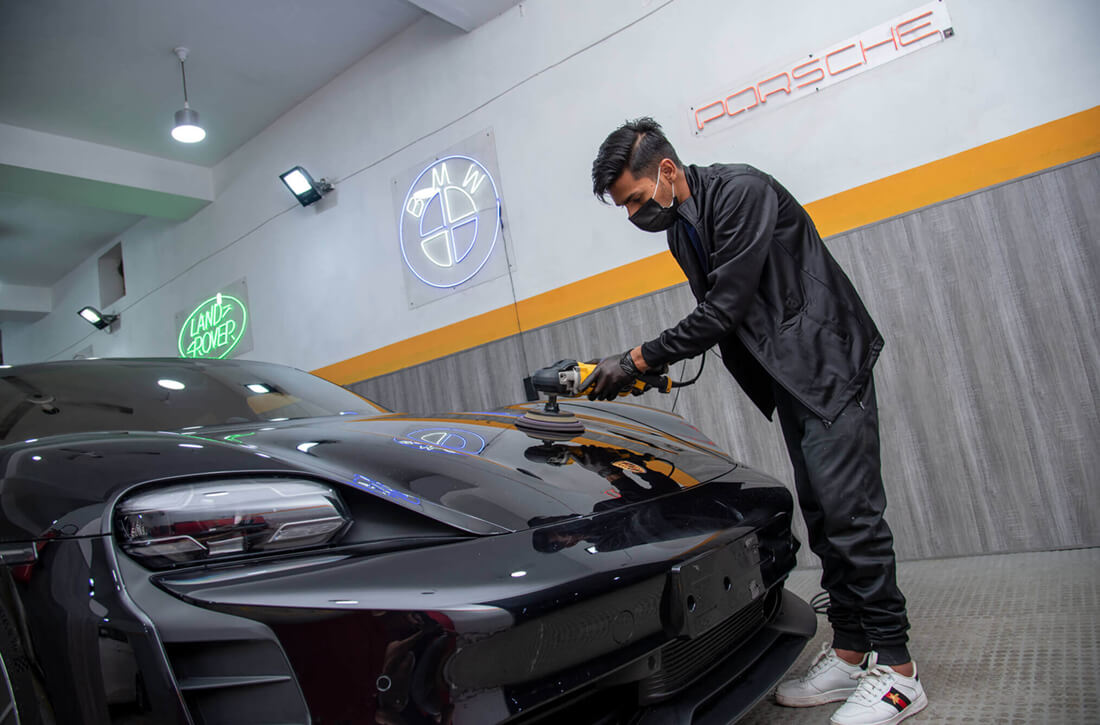 professional detailing guy is polishing the paint surface of porsche taycan at demnok restorations lahore